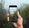 African-American man using weather forecast app on smartphone near window, closeup