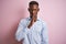 African american man wearing blue elegant shirt standing over  pink background asking to be quiet with finger on lips