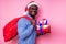 African American man wearing stylish plaid shirt great smile in santa hat with gift box on pink background studio.dark