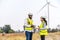 African american man and woman engineers in uniform discuss and use tablet working stand near wind turbines ecological energy