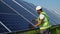 African american mechanic in white hard hat working with screwdriver on solar panel fixing frame