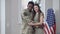 African American military husband hugging Caucasian wife and smiling looking at camera. Portrait of happy young couple