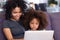 African American mom and daughter relax using laptop together