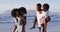 African american mother and father giving a piggyback ride to their daughter and son at the beach