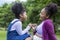 African American mother is giving pinky promise to her young daughter while having a summer picnic in the public park for love and