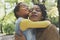 African American mother hugging her little daughter in meadow.