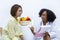 African American nutritionist with bowl of variety of fruit and vegetable giving advice to the client for healthy diet and vitamin