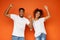 African-american partners rejoice success together on orange background