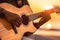 African american person\\\'s hands playing acoustic guitar on sandy beach at sunset time. Playing music concept, neural network