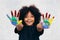 African American playful and creative kid getting hands dirty with many colors