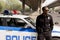 african american police officer leaning back on car