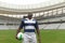 African American rugby player standing with rugby ball and looking up in stadium