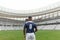 African American rugby player standing with rugby ball in stadium