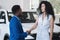 African American salesman gives key to bought car to client