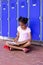 African american schoolgirl sitting next to lockers in corridor at school