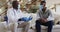 African american senior male doctor giving covid test to male patient in home, wearing face masks