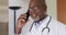 African american senior male doctor wearing white coat talking on smartphone