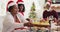 African american senior woman in santa hat passing the food plate of her son and grandson while sitt