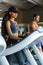 african american slim woman with her black handsome athletic trainer on the treadmill in gym. Fitness concept