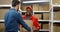 African American smiled cheerful postman giving carton box to Caucasian client in postal office store.