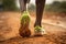 African-American sportsman in sneakers runs along dirt track at countryside closeup