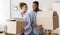African American Spouses Carrying Moving Boxes Smiling Standing Back-To-Back Indoor