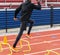African American sprinter perfoming speed drills over yellow mini hurdles on a track