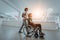 African American student pushing his friend& x27;s wheelchair through a modern school, demonstrating inclusion