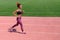 An African American in the summer sports. A young sporty black girl runs along the pink path of the stadium next to
