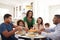 African American  three generation family sitting together at the kitchen table, with grandmother serving food, close up