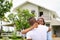 African American wife hugging her husband in front of the house they just move in while holding key for housing and relocation