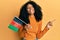 African american woman with afro hair holding afghanistan flag smiling happy pointing with hand and finger to the side