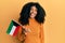 African american woman with afro hair holding kuwait flag looking positive and happy standing and smiling with a confident smile