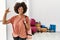 African american woman with afro hair holding yoga mat at pilates room smiling and confident gesturing with hand doing small size