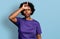 African american woman with afro hair wearing casual purple t shirt making fun of people with fingers on forehead doing loser