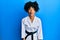 African american woman with afro hair wearing karate kimono and black belt making fish face with lips, crazy and comical gesture