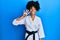 African american woman with afro hair wearing karate kimono and black belt showing and pointing up with fingers number four while