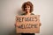 African american woman asking for immigration holding banner with wlecome refugees message with a happy face standing and smiling