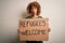 African american woman asking for immigration holding banner with wlecome refugees message scared in shock with a surprise face,