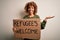 African american woman asking for immigration holding banner with wlecome refugees message very happy and excited, winner