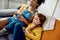 African american woman, baby sitter and caucasian cute little girl having fun together, playing video games, sitting on