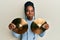 African american woman with braided hair holding golden cymbal plates puffing cheeks with funny face