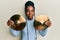 African american woman with braided hair holding golden cymbal plates relaxed with serious expression on face