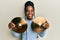 African american woman with braided hair holding golden cymbal plates smiling with a happy and cool smile on face