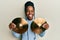 African american woman with braided hair holding golden cymbal plates sticking tongue out happy with funny expression