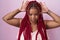 African american woman with braided hair standing over pink background doing bunny ears gesture with hands palms looking cynical