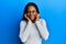 African american woman with braided hair wearing casual white sweater covering ears with fingers with annoyed expression for the