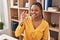 African american woman with braids sitting at dinning room doing ok sign with fingers, smiling friendly gesturing excellent symbol