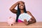 African american woman with braids sitting on the table with piggy bank and dollars stressed and frustrated with hand on head,