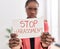 African american woman business worker holding stop harassement banner at office